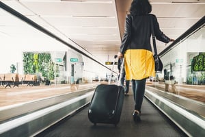 Woman pulling suitcase on moving walkway